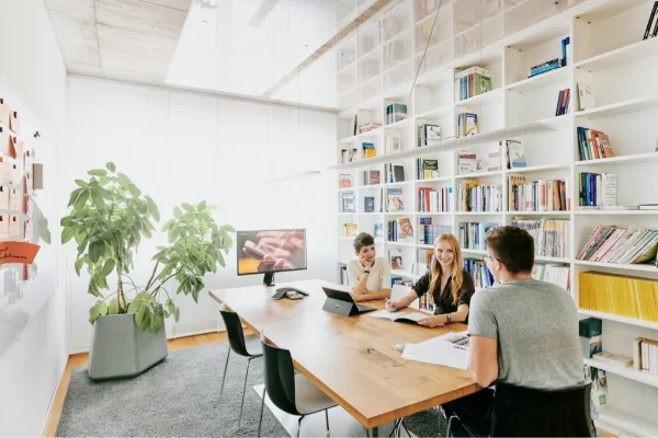 3 Kolleg:innen beim Brainstormen in der Bibliothek